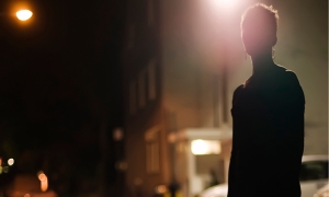 Silhouette of a woman on a street corner at night